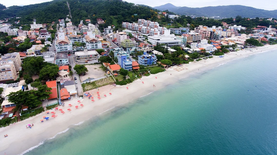 Vista aérea da praia de Bombinhas com mar verde e morros (SC)