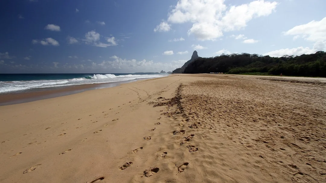 Faixa de areia da Cacimba do Padre com morros ao fundo, em Fernando de Noronha (PE)