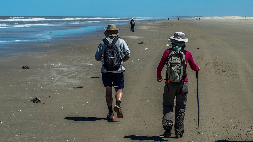Caminhantes na larga faixa de areia da Praia do Cassino, em Rio Grande (RS)