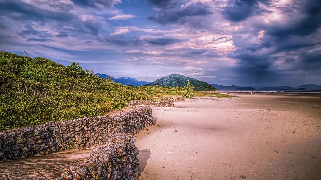 Faixa de areia da Praia de Guaratuba, com a serra ao fundo, em Bertioga (SP)