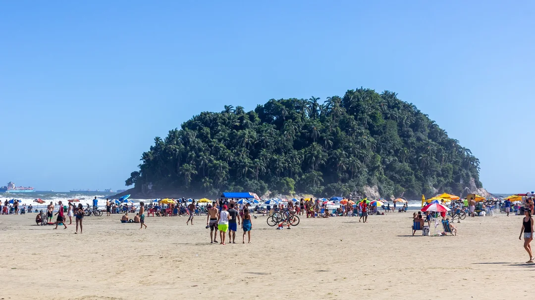 Banhistas na areia da Praia do José Menino diante da Ilha Urubuqueçaba, em Santos (SP)