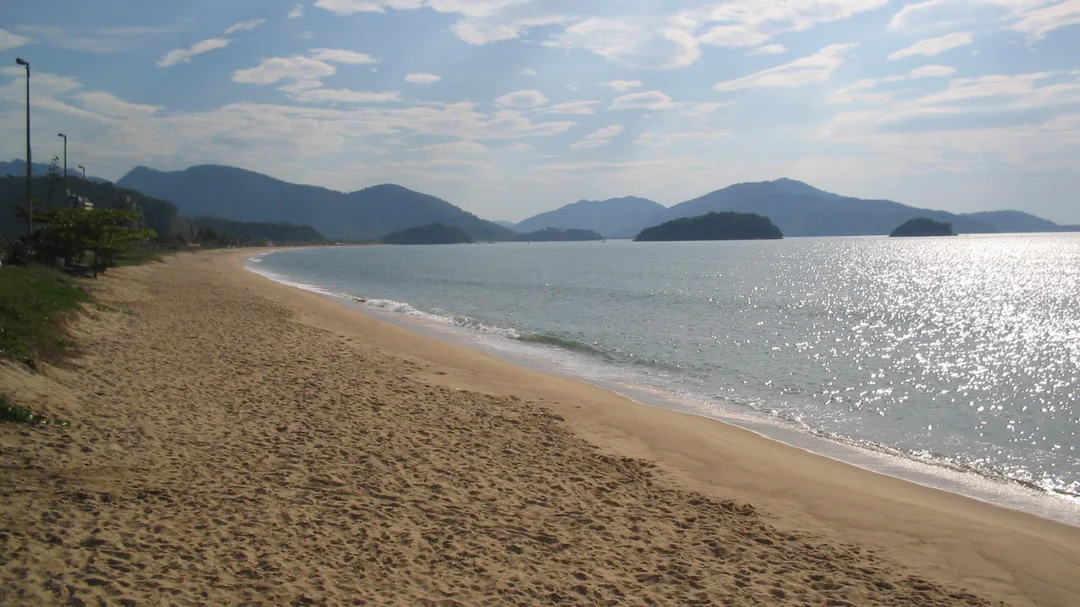 Faixa de areia da Praia de Massaguaçu, com ilhas e montanhas ao fundo, em Caraguatatuba (SP)