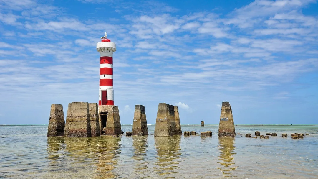 Farol listrado entre pilares no mar da Ponta Verde, em Maceió (AL)