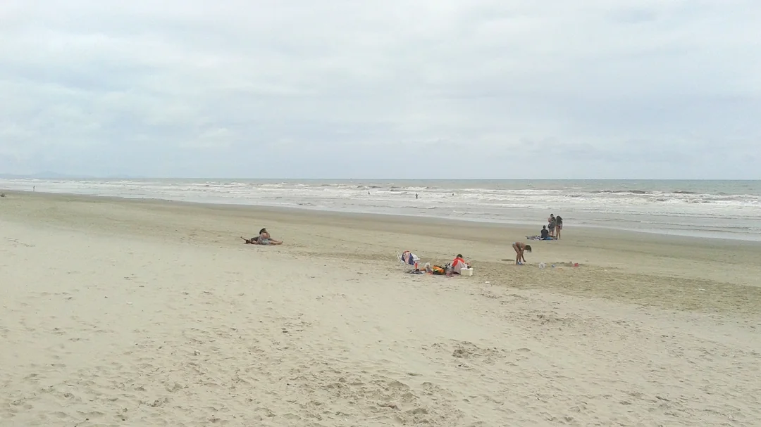 Faixa larga de areia e mar aberto na Praia Central de Mongaguá, em Mongaguá (SP)