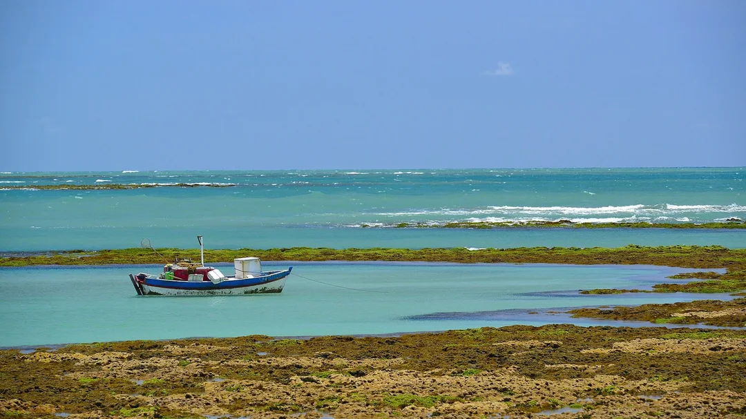 Piscinas naturais e barco na maré baixa da praia do Seixas, em João Pessoa (PB)