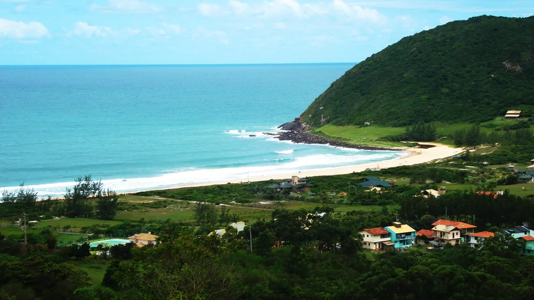 Enseada e mar verde da Praia do Silveira vistos do morro, em Garopaba (SC)